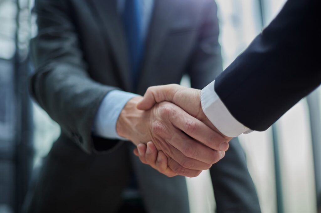 Business leaders shaking hands to close a healthcare merger that requires enterprise fax consolidation
