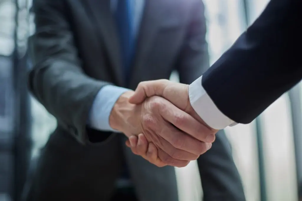 Business leaders shaking hands to close a healthcare merger that requires enterprise fax consolidation