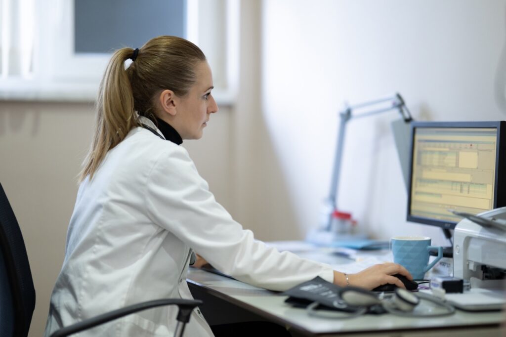 Physician working at a clinic computer with clinical fax workflow integration built into the EHR