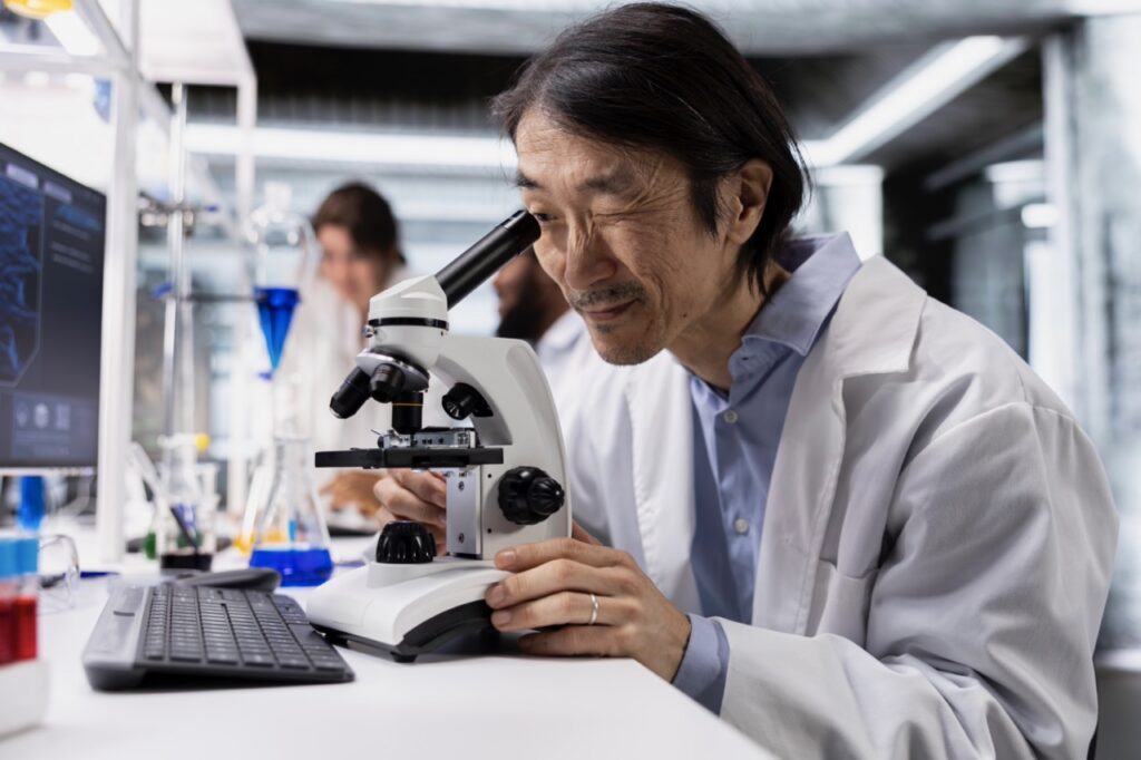 Laboratory technician at a microscope, where automated fax transmission sends finalized results