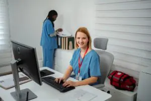 Smiling nurse working at a computer where healthcare fax infrastructure runs smoothly in the background