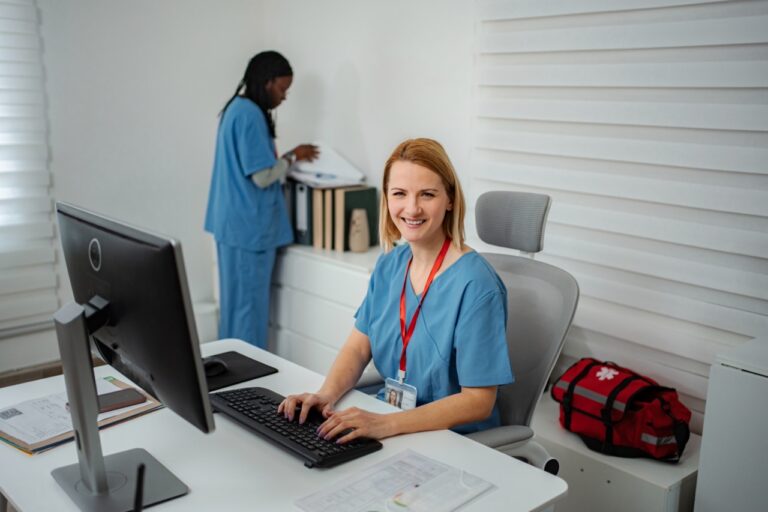 Smiling nurse working at a computer where healthcare fax infrastructure runs smoothly in the background